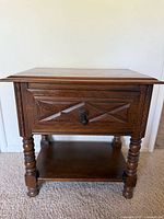 Full view of wooden nightstand showing cabinet door, turned legs and lower shelf