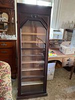 Full frontal view of tall wood cabinet with glass door and visible shelves