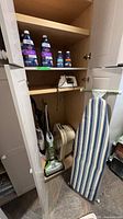 Open cabinet showing CrossWave vacuum, Reliable mop, iron, cleaning solutions