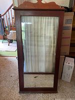 Full view of wooden linen cabinet with glass door, curtain inside