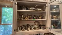 Cabinet with three shelves full of silver-plate items