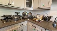 Wide view of countertop showing majority of silver-plate and pewter items including trays, chafing dish, teapot, basket, napkin rings and flatware boxes