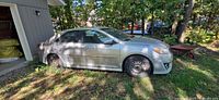 Left side view of silver 2014 Toyota Camry parked on grass