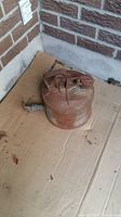 Top and side view of rusted cylindrical gas container on cardboard