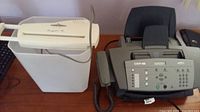 Fax machine and shredder side by side on table