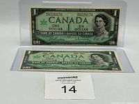 Obverse of both 1967 $1 notes in sleeves showing Queen Elizabeth II and centennial text