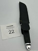 Knife in sheath next to lot number tag