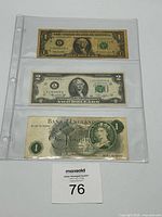 Fronts of three banknotes in plastic sleeve