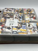 Binder closed showing first sleeve with nine hockey cards (Boston Bruins players visible)
