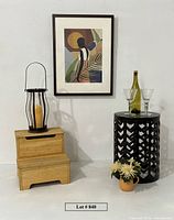 Overall lot showing table, artwork, stool, lantern, glasses, bottle, flowers