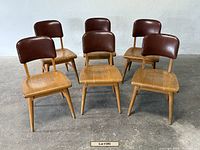 Front view of six oak side chairs with brown leather backs