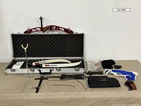 Full view of bow set inside open hard case with riser, limbs, stabilizers, sight, strings, stand and accessories