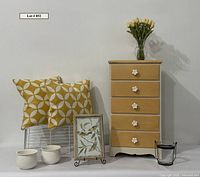 Group shot showing dresser, pillows, planters, artwork, wire basket, vase with tulips, candle holder
