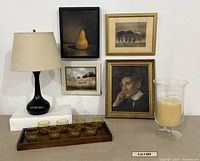 Group shot: four framed artworks, lamp, hurricane vase with candle, eight amber glasses on wooden tray