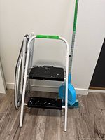 Step stool, broom with dustpan, ironing board grouped together