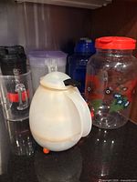Group view: egg dispenser, floral jar, shaker bottle, measuring cup, purple-lid bottle, blue-lid bottle