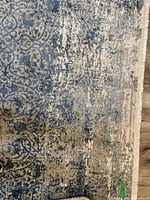 Close-up of rug corner showing distressed navy and beige pattern and pile texture