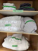 Three shelves with five bundled king bedding items labeled on green tape