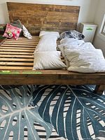 Front view of king-size rustic solid wood platform bed frame with headboard and slat support