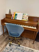 Front view of Mason & Risch upright piano with sheet music on stand and desk chair in front