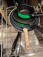 Stacked cookware showing frying pans, saucepan and cast-iron skillet
