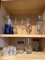 Upper shelf: blue-speckled tumblers, clear wine glasses, confetti goblet, etched goblets