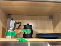 Moka pot, French press and stacked blue plates on shelf