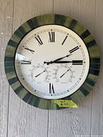 Front view of round outdoor clock showing bezel, dial, and gauges