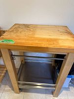 Front view of cart highlighting butcher block top, wood frame, stainless rails