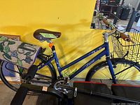 Full view of blue Trek step-through bicycle with front basket, rear rack, pannier cover, brown saddle, brown grips