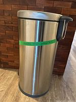 Full view of stainless steel cylindrical garbage bin showing lid and pedal