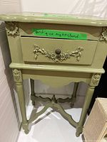 Front angled view showing entire olive painted nightstand with drawer and carvings