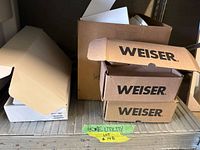Shelf with three stacked Weiser lockset boxes and additional open cardboard packaging