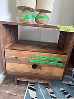 Front view of West Elm wood nightstand showing open shelf, drawer with round pull, and lamps on top (lamps not included)