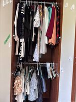 Full view of wardrobe showing upper and lower rods with assorted women’s clothing and hangers
