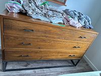 Front view of wood dresser showing three drawer fronts and metal base