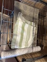 Folded striped tablecloth, placemats, and shelf liner roll on wire shelf