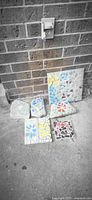 All six handmade mosaic tiles leaning against brick wall