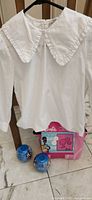 Blouse on hanger with blanket package and two toy capsules below