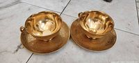 Two gold embossed teacup and saucer sets view