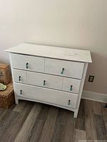 Front view of the white dresser showing three drawers and hardware