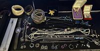 All jewelry pieces laid out on black surface showing variety and quantity