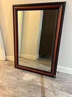 Full view of wood-framed mirror leaning against wall