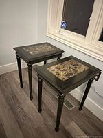 Two matching end tables showing tops with faux marble inserts and leg design