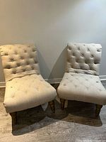 Front view of both beige tufted chairs showing overall design and condition