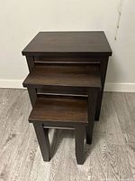 Three dark brown wooden nesting tables stacked
