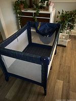 Overall view of assembled Graco travel crib showing mesh sides and plaid fabric