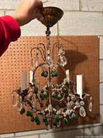 Full view of chandelier showing brass frame, crystal prisms, green drops, candle sockets and canopy