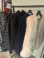 Rack with five garments: fur vest, trench, puffer jackets