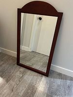 Full view of wood-framed mirror leaning against wall